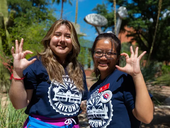 Destination Arizona Leaders, Karime and Chi, pose for the camera smiling with the cat claw. 