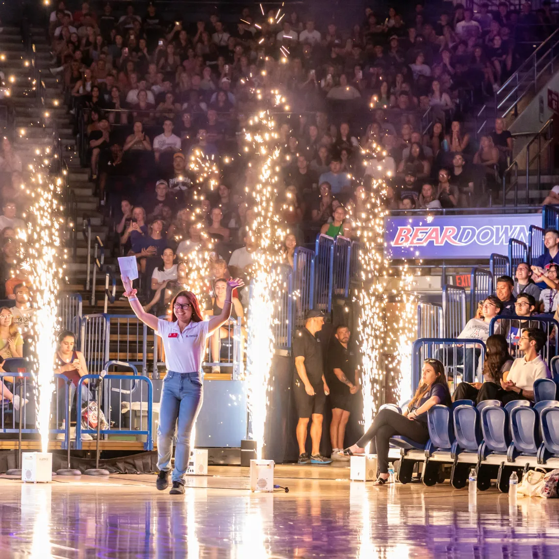 Destination Arizona Leader, Trin, smiling as they enter McKale Memorial Center through cold-spark fireworks. 